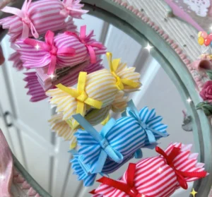 Sweet lolita candy striped hair clips and brooches collection overhead view displayed on vintage mirror with pastel desktop aesthetic sparkly embellishments