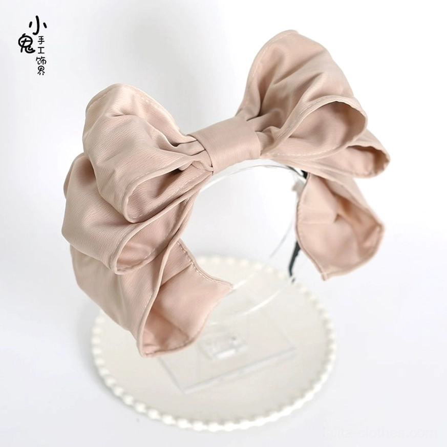 Champagne khaki oversized satin bow hair clip frontal side view on decorative plate stand neutral khaki color double-layered satin bow