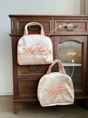 Two champagne Lolita petticoat storage bags in Small and Large sizes displayed on a vintage wooden dresser with embroidered details, orange trim, and carry handles