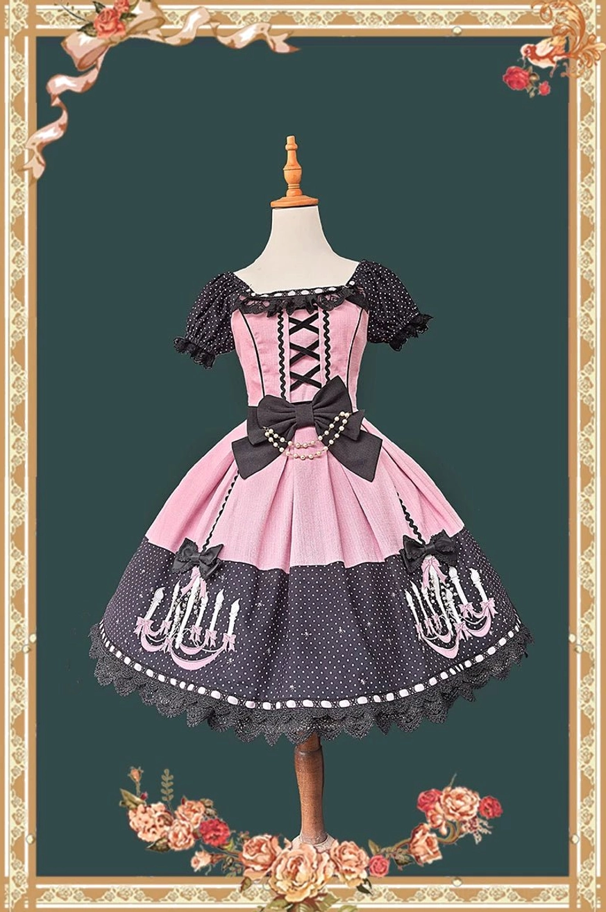 Front view of pink and black vintage chandelier polka dot old school lolita OP dress with off-the-shoulder ruffled sleeves, lace-up corset, and scalloped skirt trim on wooden dress mannequin