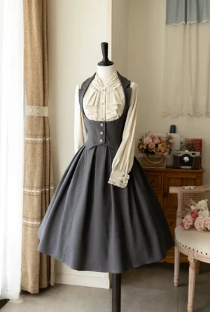 Dark charcoal grey classic lolita JSK jumper skirt with cream ruffled collar blouse, retro corset-style bust-support bodice, full pleated midi skirt, displayed on dress mannequin in vintage bedroom setting with decorative florals
