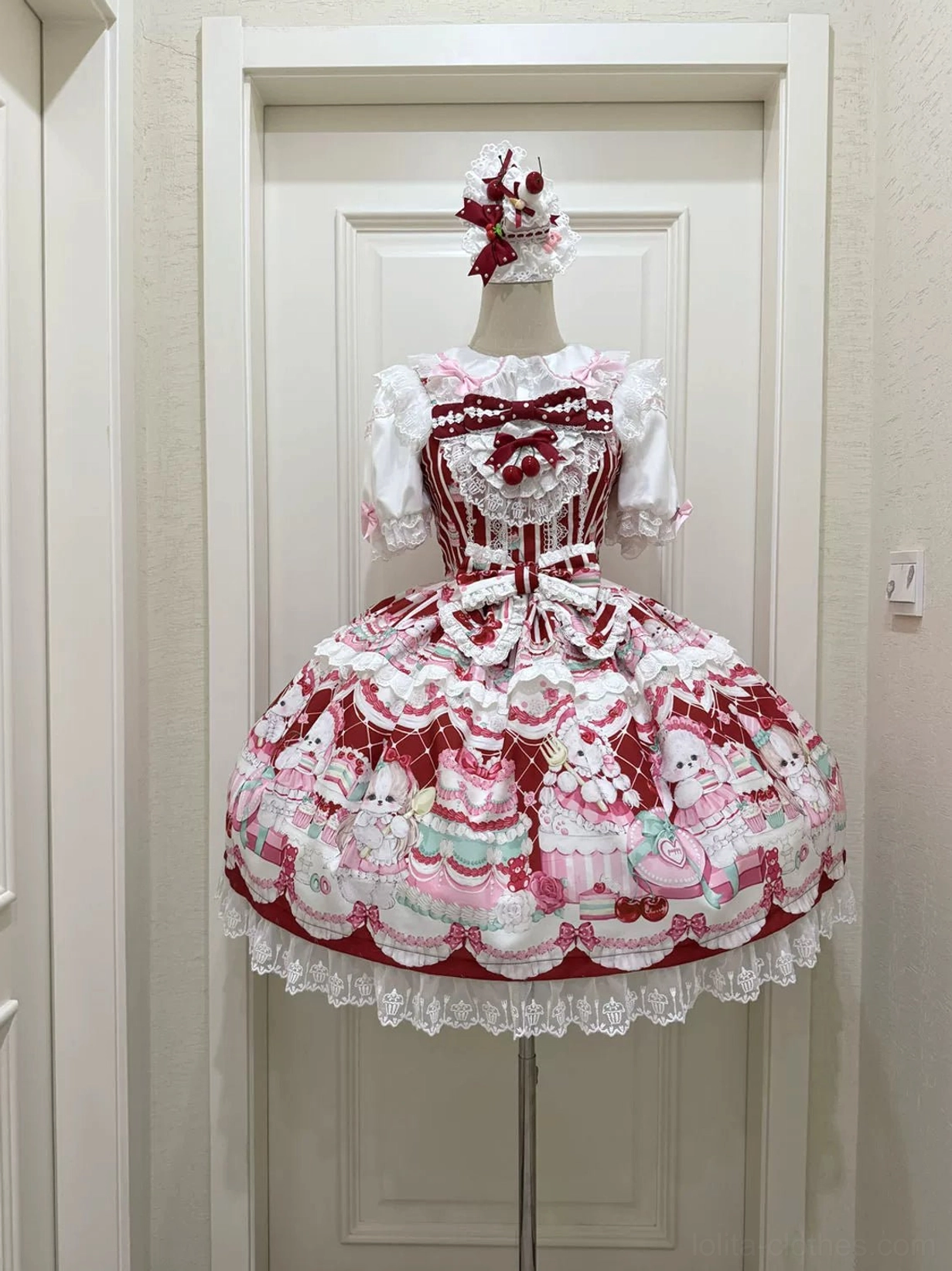 Cherry Bake Song Lolita JSK Dress burgundy version on dress form, flat display front view showing full dessert print pattern, heart-shaped bow on lace collar, and ruffled lace skirt hem detail