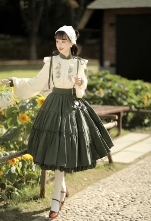 Pastoral Lolita two-piece outfit side view showing high-waisted layered green skirt and embroidered lantern sleeve blouse on model in sunflower garden setting