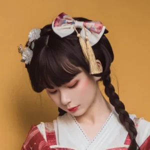 Chinese-style lolita hair clip set with pink-white gradient bow and golden tassel pendant worn with red hanfu lolita dress, floral metal ornaments and double braided hairstyle