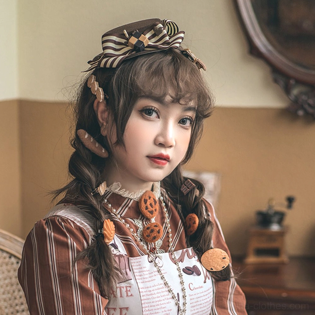 Front three-quarter view of striped bow lolita beret with multiple cookie decorative pendants and biscuit charms, worn by model in brown striped coordinate in vintage home interior background