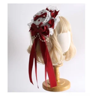 Front three-quarter view of red and white Christmas Lolita headband with large satin bows, pearl chain accents, and ruffled lace trim on blonde mannequin head display