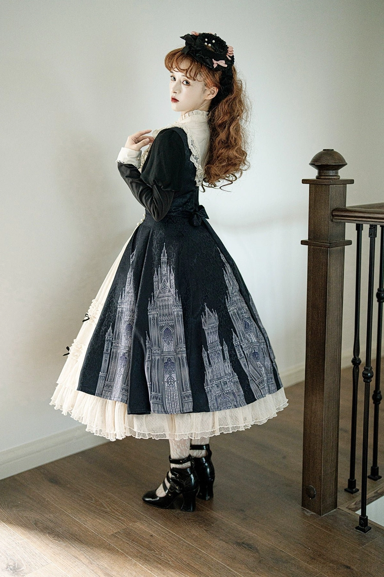Church Bell gothic lolita OP dress back three-quarter view showing full flowy A-line skirt with layered hem detail and matching leather platform shoes on stairwell