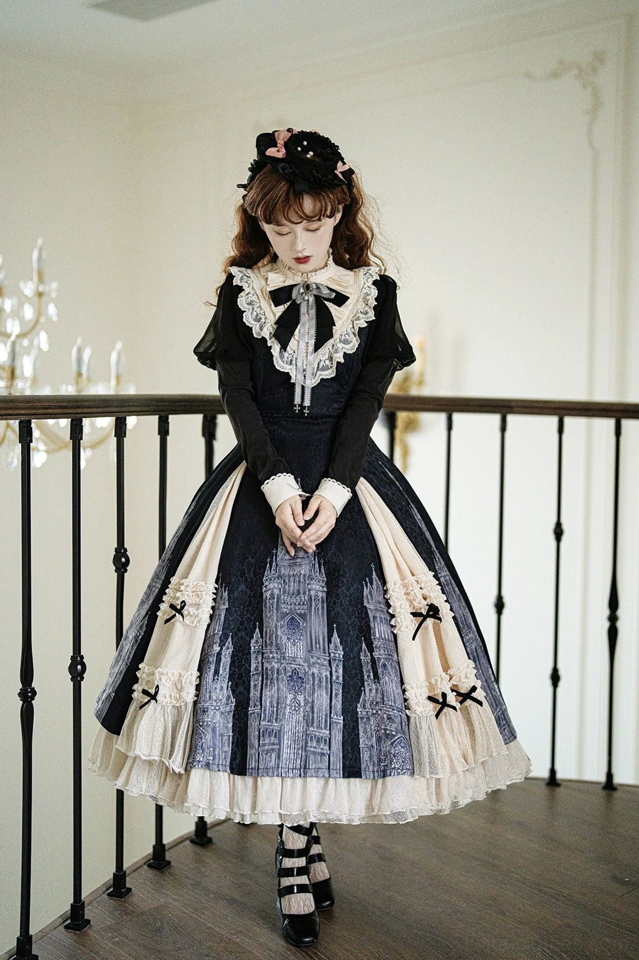 Church Bell gothic lolita OP dress full front view with hands clasped showing neat A-line skirt, layered tulle hem, and central cathedral print on skirt body near staircase
