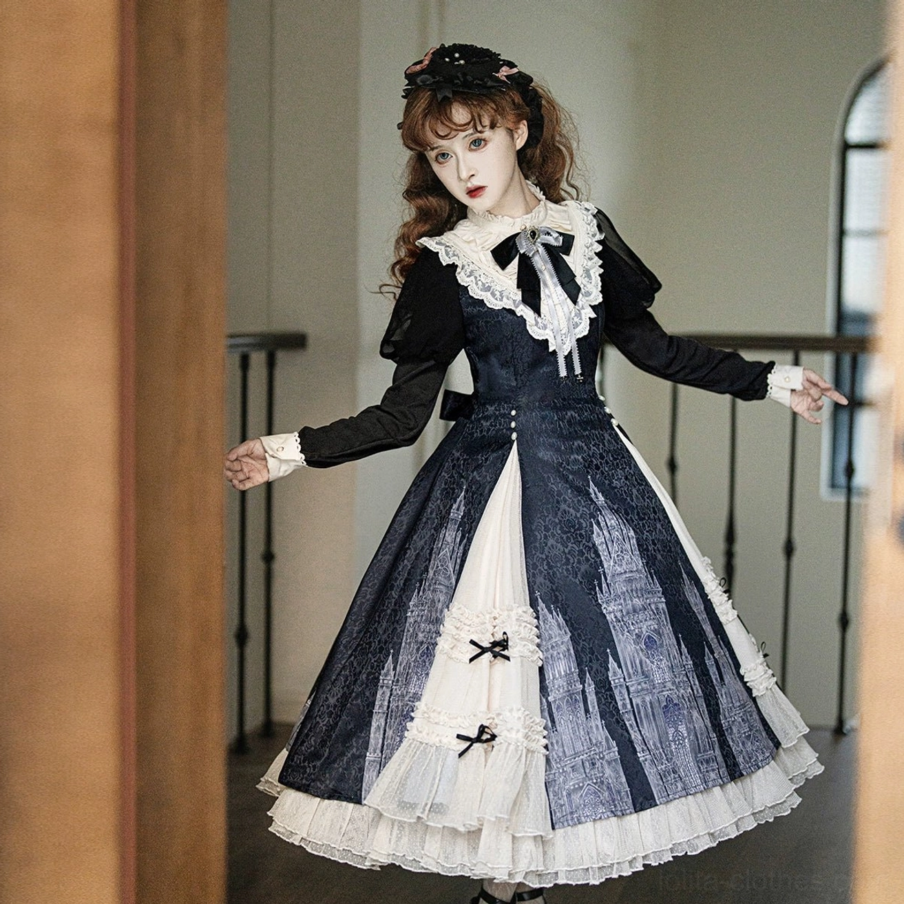 Church Bell gothic lolita OP dress side three-quarter view demonstrating fitted waist, white ruffled cuffs, and small black bow details on front skirt panels in villa hallway