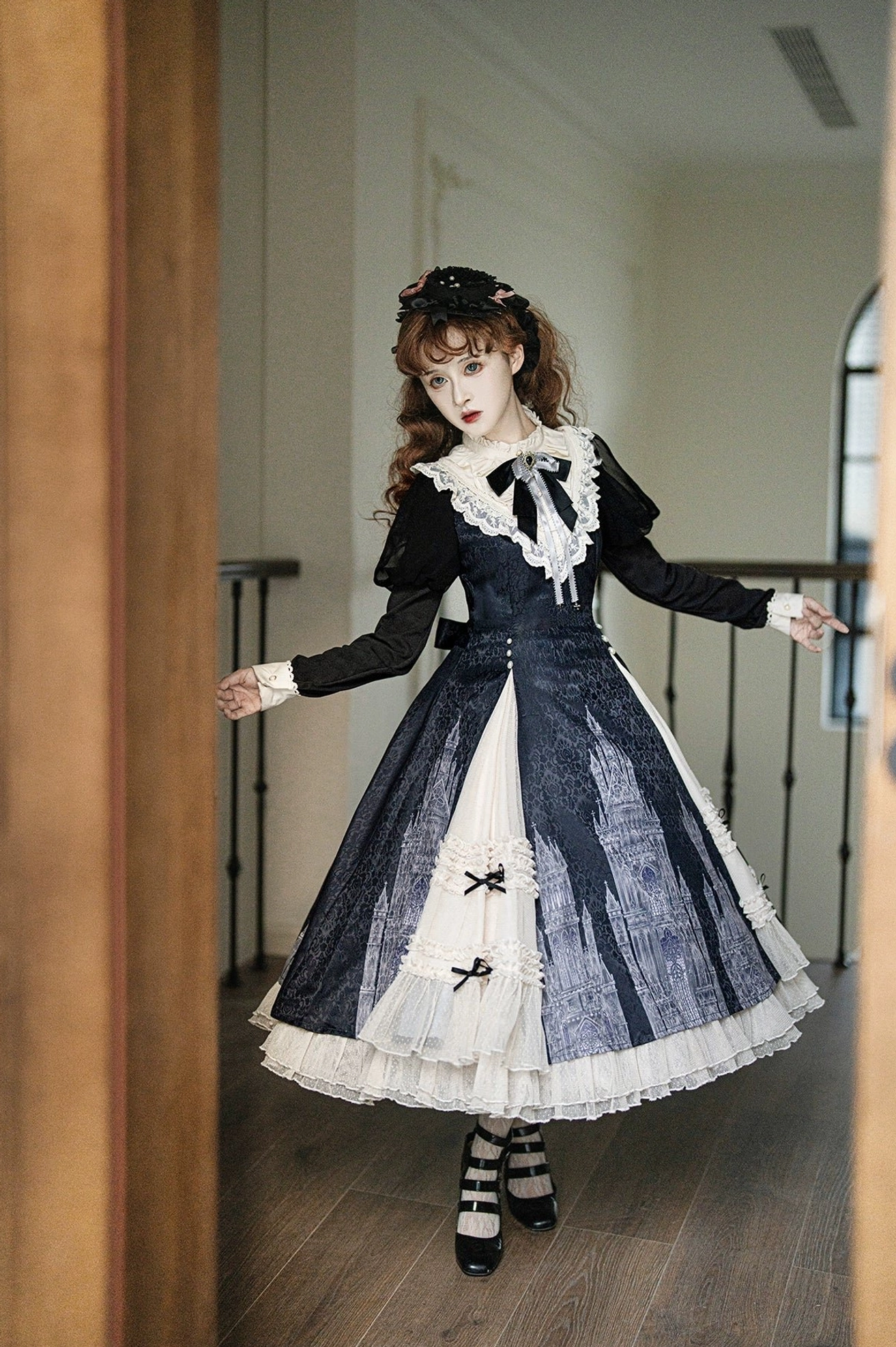 Church Bell gothic lolita OP dress side three-quarter view displaying fitted long black sleeves, ivory contrast skirt panels, and delicate lace collar trim in villa setting