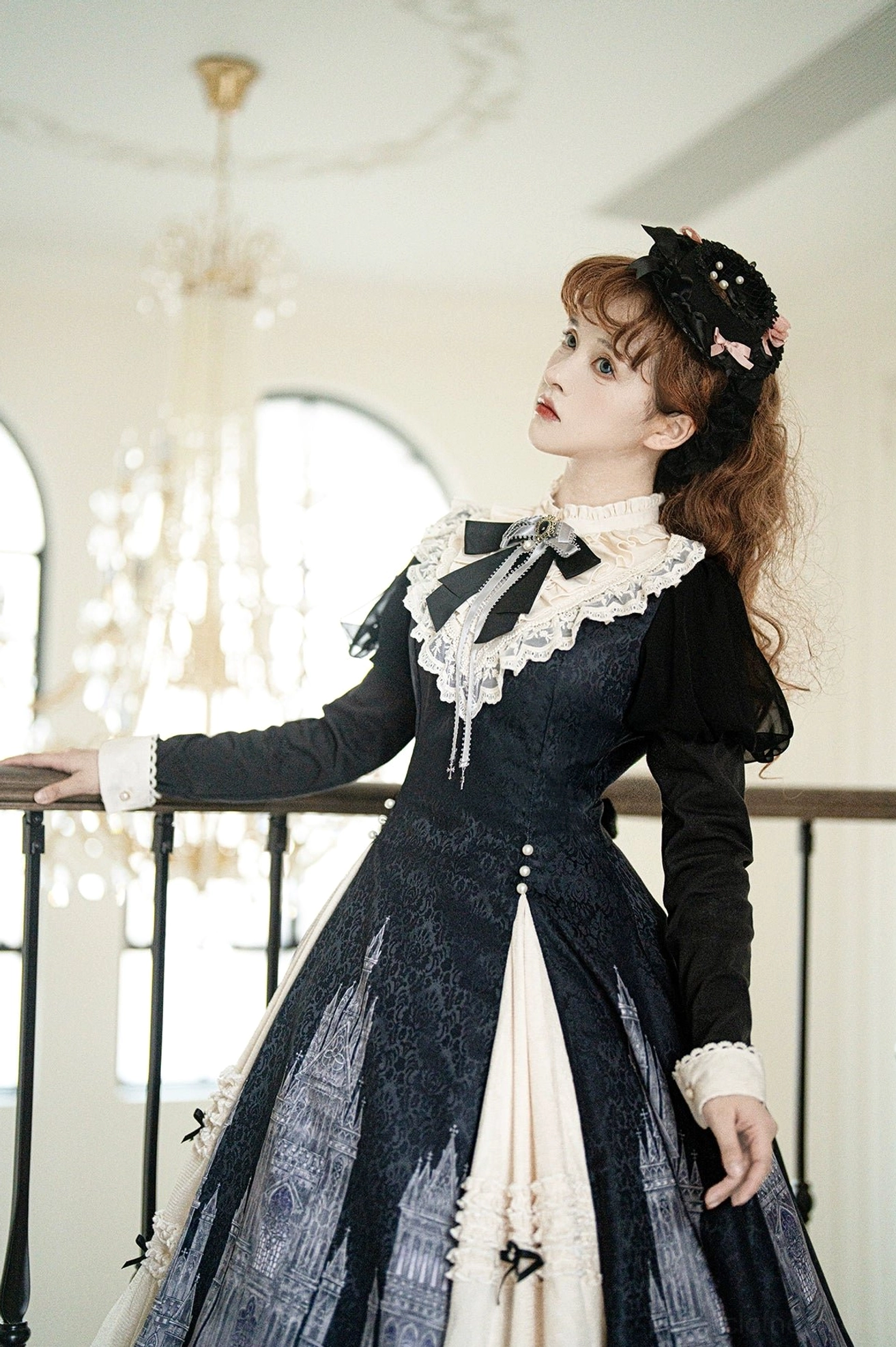Church Bell gothic lolita OP dress side three-quarter view leaning on balcony railing showing neck lace bow, white ruffled cuffs, and classic lolita silhouette with arched window background