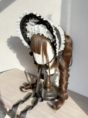 Classic Lolita bonnet in black with white ruffled lace trim, left side profile view on mannequin with brown twin ponytails, showing decorative ribbon on brim and structured hat shape