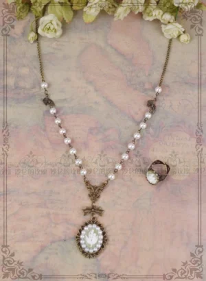Classic cameo lily necklace with pearl-accented bronze chain pendant displayed on decorative vintage board, showing pendant detail and matching tiny open ring on antique map background