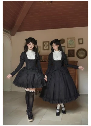 Medium shot of two female models wearing matching lolita blouse and skirt suit with contrast white lace collar, boned corset-style bodice, ruffled hem in studio setting with tiled backdrop, styled with black platform loafers and thigh-high socks