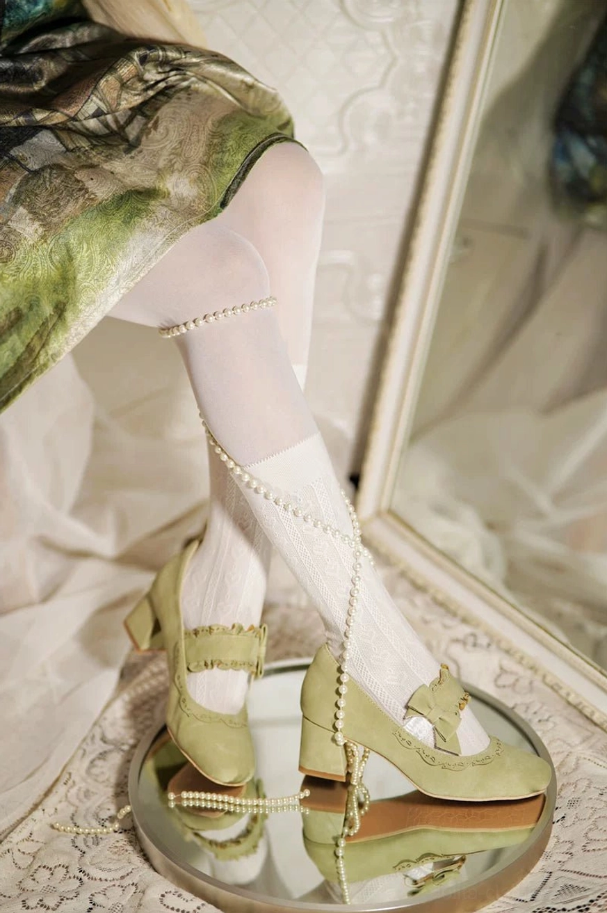 Sage green classic lolita chunky heel mary jane shoes with cutout trim details and decorative bow ankle strap, worn with vintage print skirt and white stockings with pearl ankle chain, low-angle mirror reflection shot