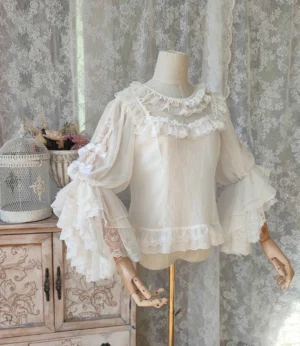 Off-white classic Lolita hime-sleeve blouse with ruffled round neckline and layered embroidered lace trumpet sleeves displayed on dress form with vintage lace curtain background