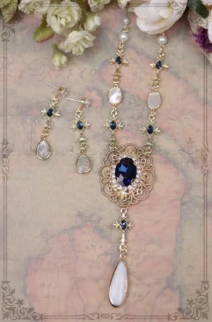 Vintage navy blue filigree lolita necklace with pearl and rhinestone details displayed on antique map background with artificial flowers, flat lay jewelry photography