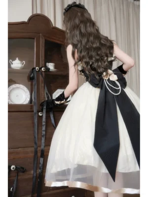 Back view of Classic Lolita jumper skirt featuring dramatic black satin bow with pearl chain accent, flowy tulle skirt with satin hem trim, elegant dress silhouette