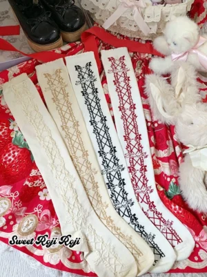 Classic Lolita mid-calf bow socks in all four colorways - black, red, ivory, and light ivory with raised textured details displayed on strawberry-themed fabric background with plush dolls