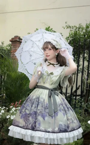Sage green classic lolita OP dress with grape and bunny print worn by model in garden setting holding lace parasol, featuring white ruffled skirt hem, matching hairband and white gloves front three-quarter view
