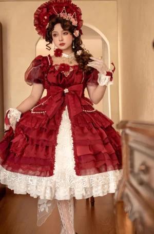 Red classic lolita plus-size OP dress front full-body shot with square neckline, puff organza sleeves, large front waist bow, and multi-layered ruffled skirt with white lace hem, modeled by vintage lolita enthusiast in period-inspired indoor setting