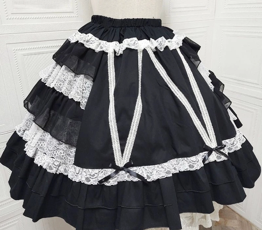 Solid black Classic Lolita tiered skirt with white lace trims and cross ribbon straps front display