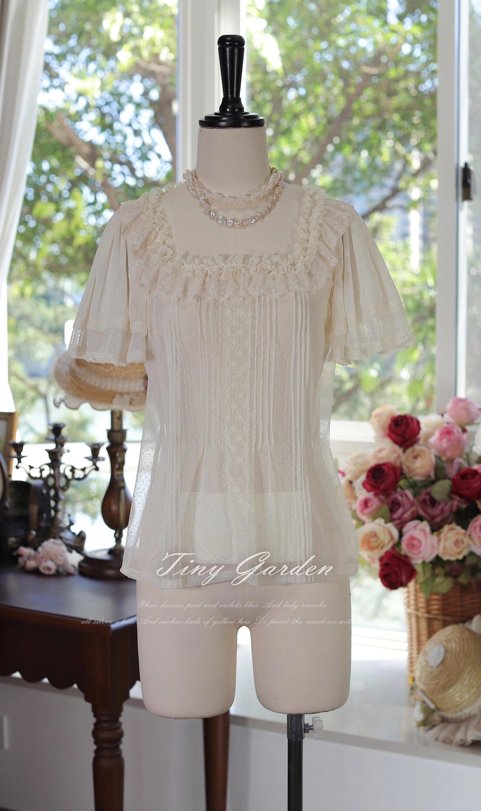 Vintage-inspired lolita square neck tulle blouse back three-quarter view displaying sheer cream beige fabric, ruffled short sleeves with flowy relaxed silhouette and delicate lace yoke detail in romantic studio setting