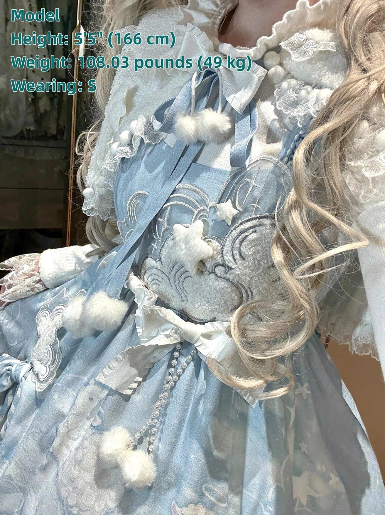 Close-up detail of Cloudscape Dream JSK upper bodice, cloud embroidery applique, white satin bow with pearl chain accents, fluffy pom-pom ornaments, smooth satin fabric texture showcase