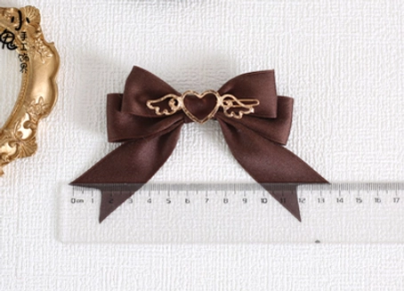 Dark brown coffee satin bow hair clip with gold heart-wing decorative charm shown with size reference ruler