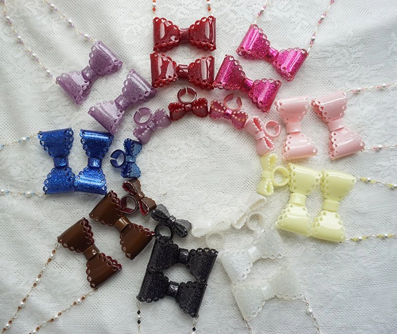 Full collection display of nine sweet lolita beaded bow necklaces in red purple blue brown black cream white and pink colors white fabric background