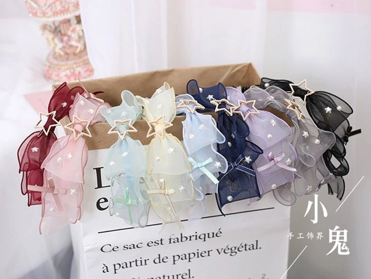Full range collection of lolita KC bow hair clips in multiple colors with star metal decor on French paper bag flat lay