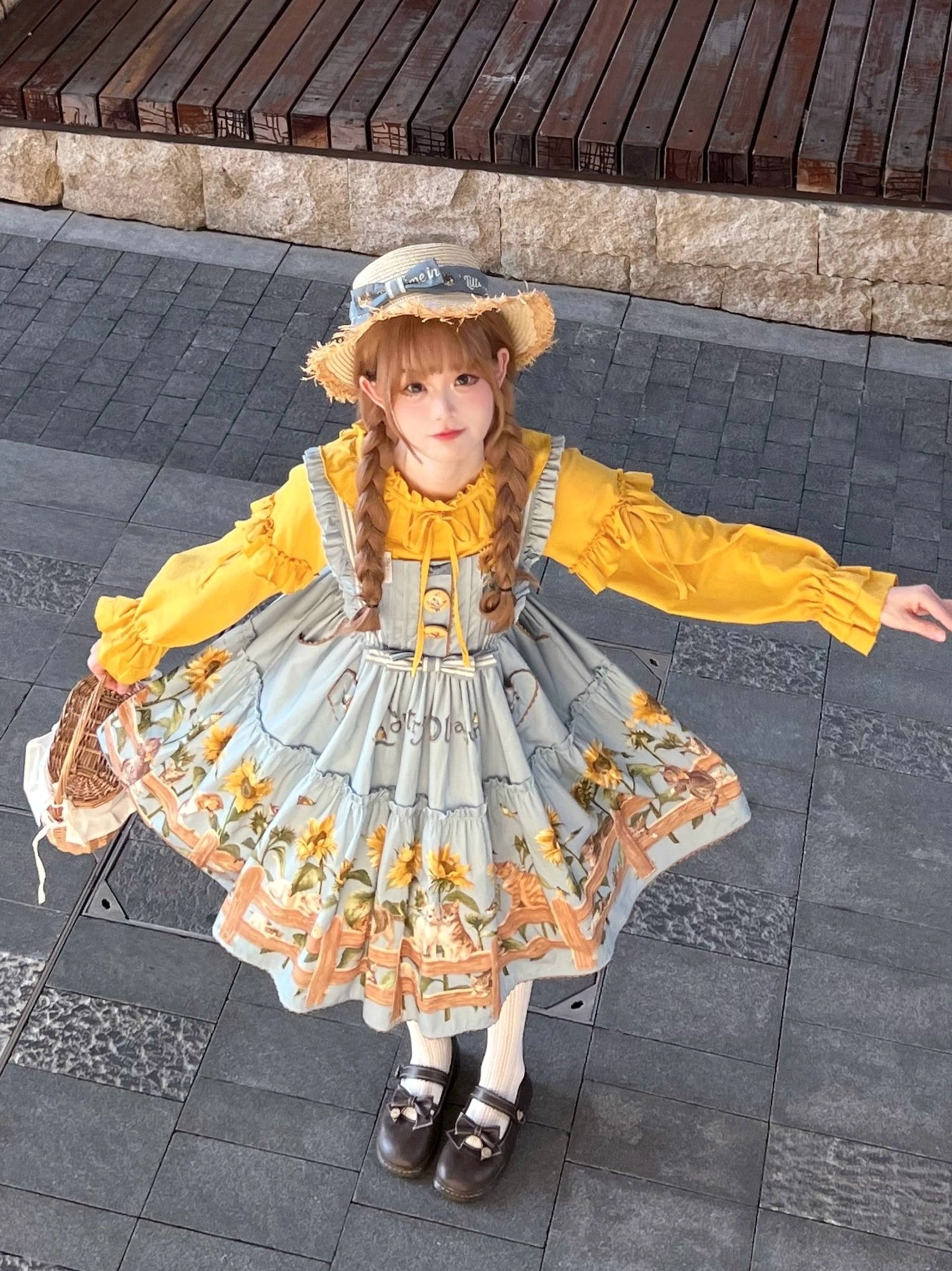 Complete country lolita outfit worn outdoors on wooden paved deck with twin braids straw hat, yellow blouse, woven bag and loafers