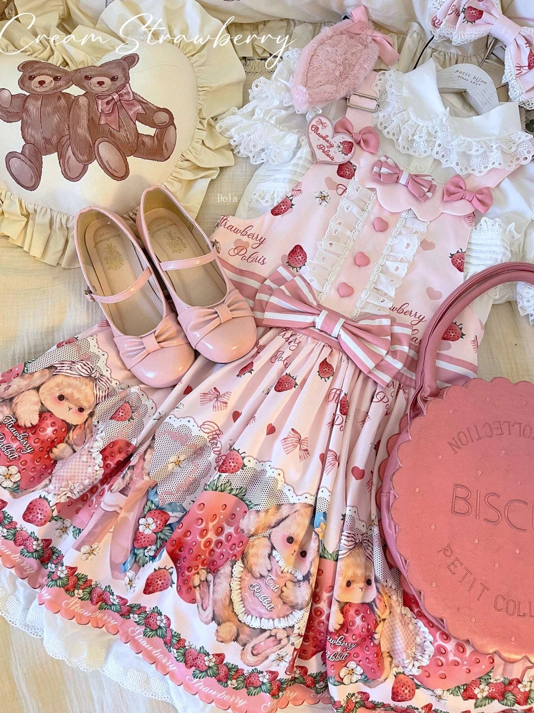 Overhead flat lay of complete strawberry rabbit lolita fashion set with salopette print dress pink mary jane shoes bows plush toys and accessories