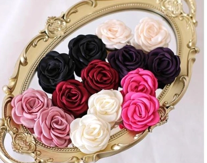 Coordinated fabric rose hair clip collection on vintage golden oval mirror tray showing smooth satin finish and handcrafted petal details