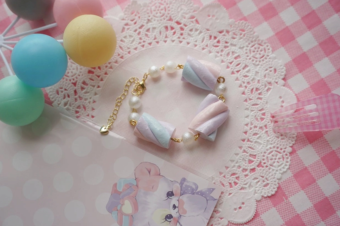 Top-down flat lay of pastel cotton candy resin lolita bracelet displaying side view and full chain length with adjustable metal clasp and cute macaron-inspired pastel color palette on decorative background