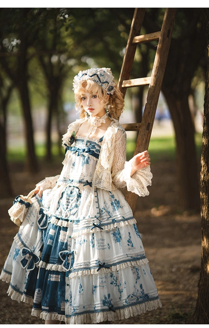 Three-quarter front view of blue and white porcelain print Lolita dress with cardigan, ruffled lace sleeves, bow decorations on skirt tiers, and straw bonnet, photographed near wooden ladder in woodland setting