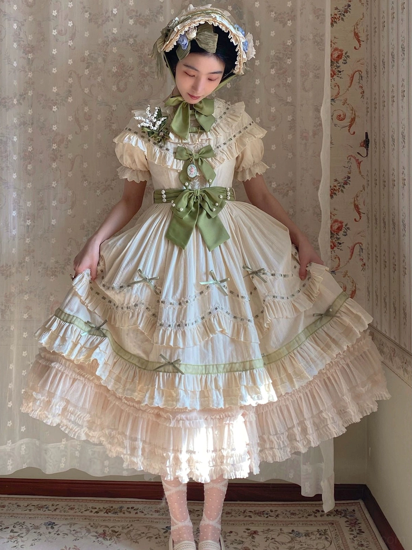 Country lolita OP dress with cascading tiered ruffles and sage green ribbon trim worn with floral hair accessory shown front view from above
