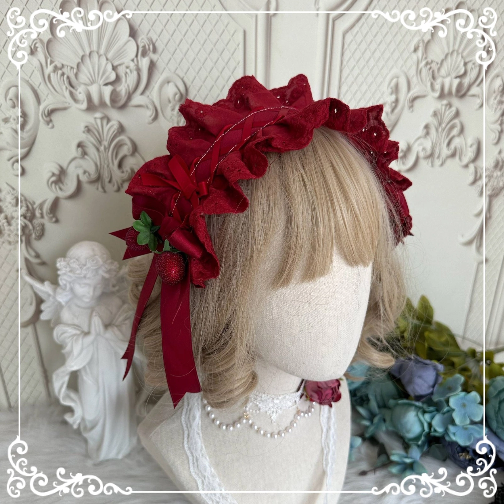 Wine red pleated lace strawberry headdress with long streamers and floral trims on mannequin head European carved background