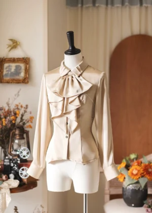 Cream beige Lolita dress shirt with layered ruffled jabot and long sleeves on mannequin, cozy vintage indoor studio decor with flowers