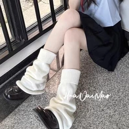 Cream beige lolita leg warmers seated low close-up side view indoor balcony metal railings black mini skirt leather loafers