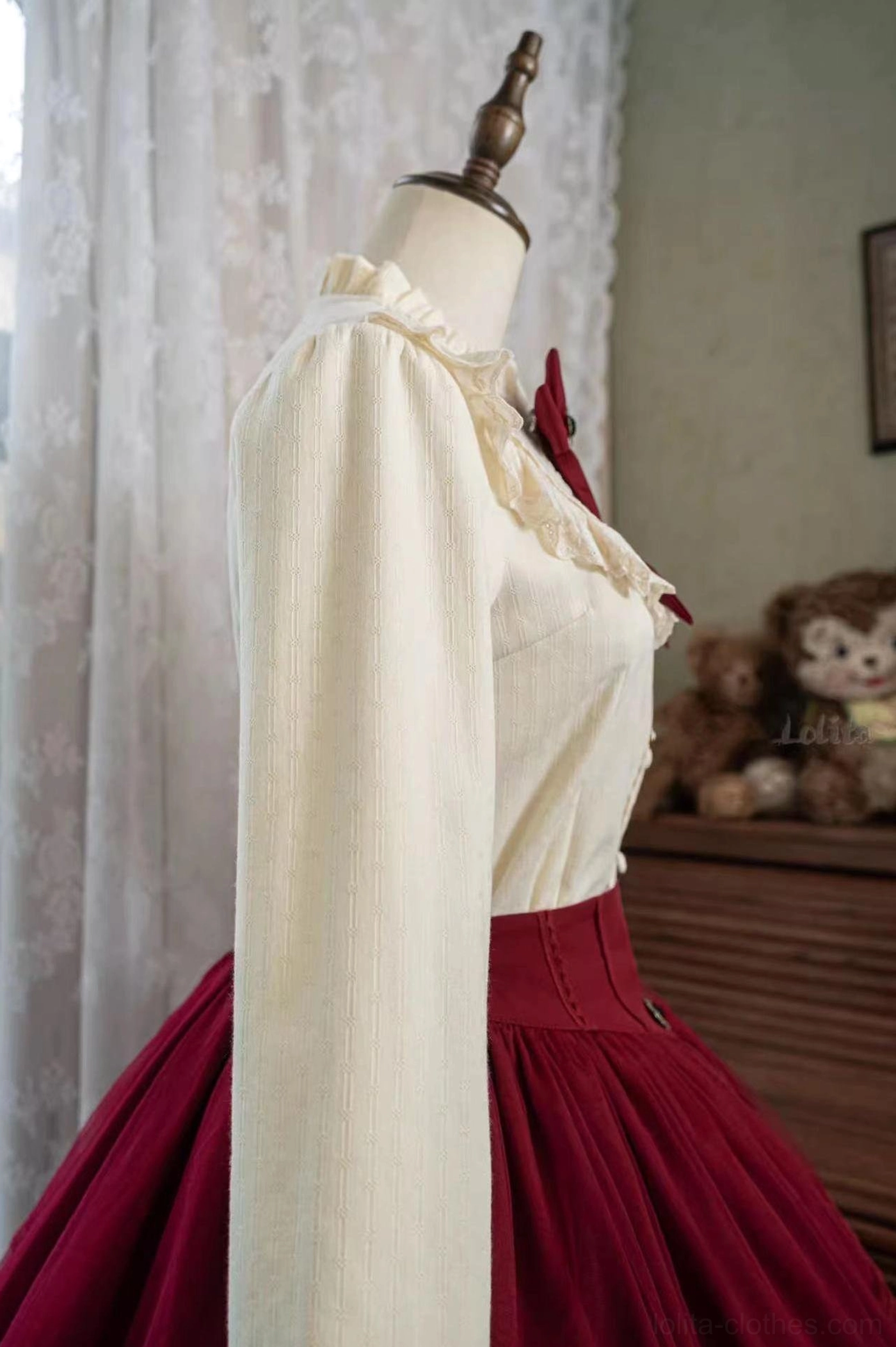 Cream fleece lolita shirt side three-quarter view on mannequin with ruffled collar trim and buttoned cuffs soft textured fabric paired with burgundy skirt