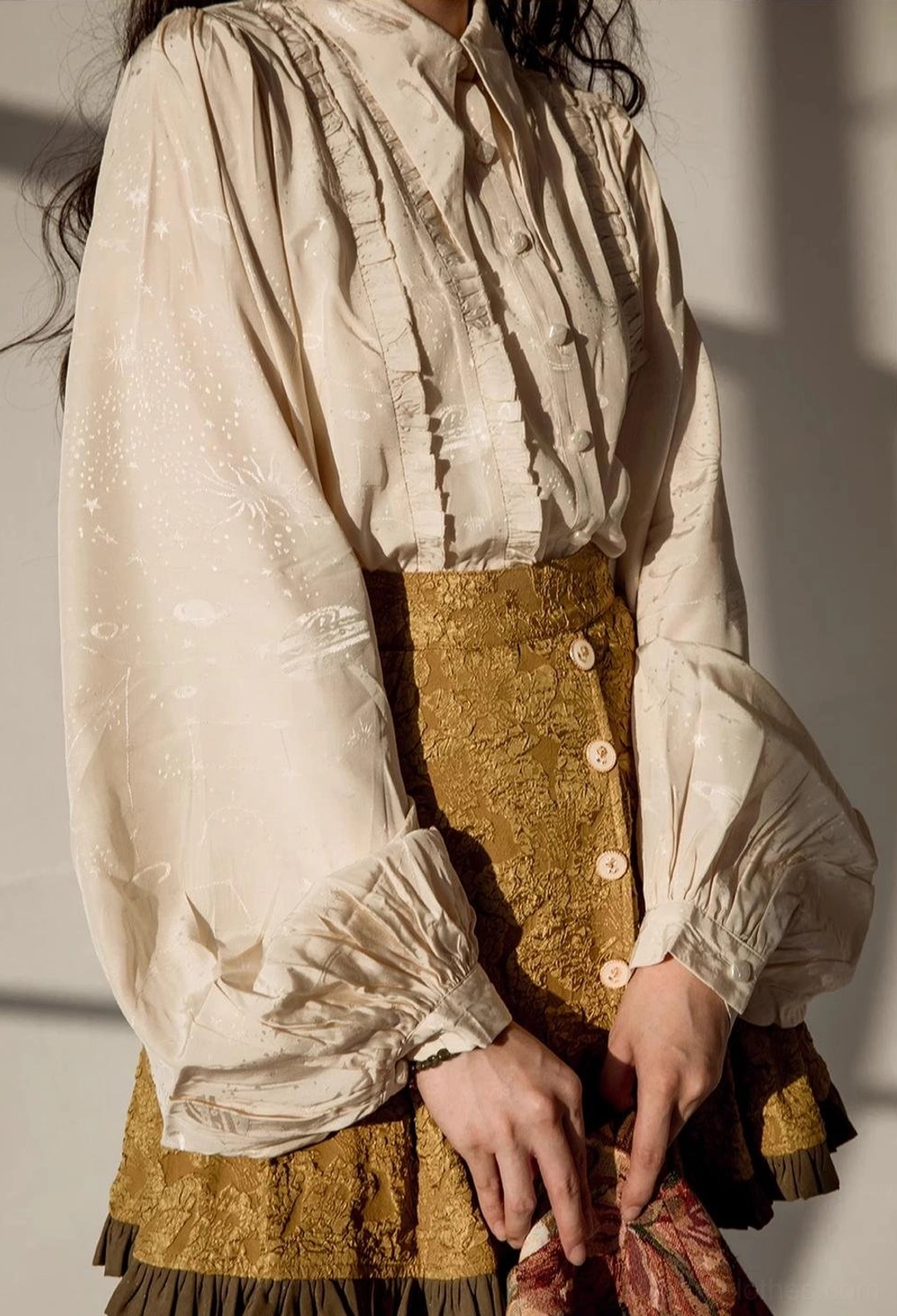 Cream colored vintage Lolita blouse half-body close-up side front view on model showing puff sleeves and ruffled front details paired with high-waisted tan skirt