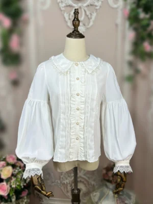 Cream-colored Lolita blouse three-quarter front angle, displaying scalloped doll collar with lace trim, pleated ruffled front, and puffed bishop sleeves with detailed cuff design