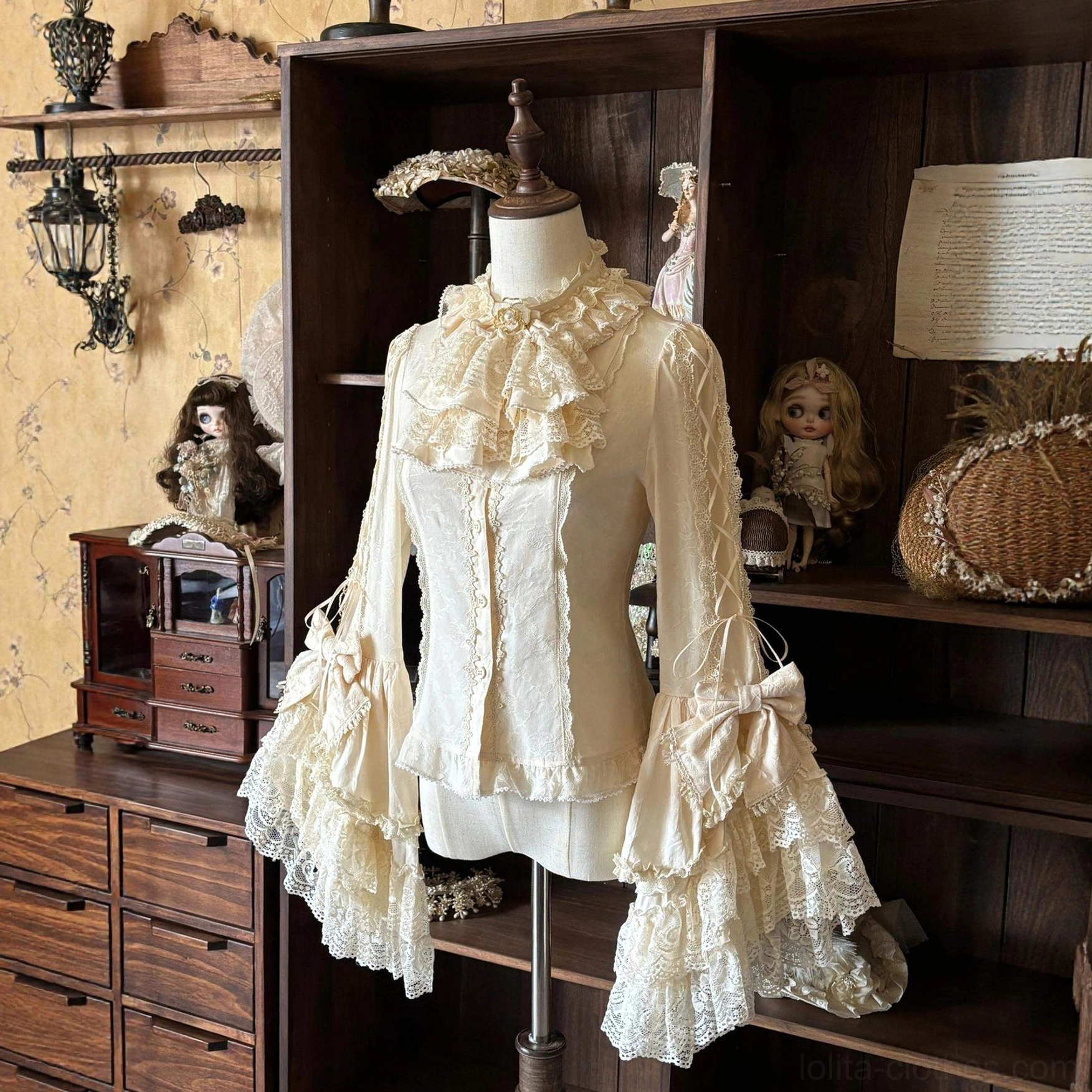Cream beige lolita hime sleeve blouse with ruffled lace jabot and sleeve bows featuring delicate lace trims and vintage aesthetic on dress form with ornamental dolls