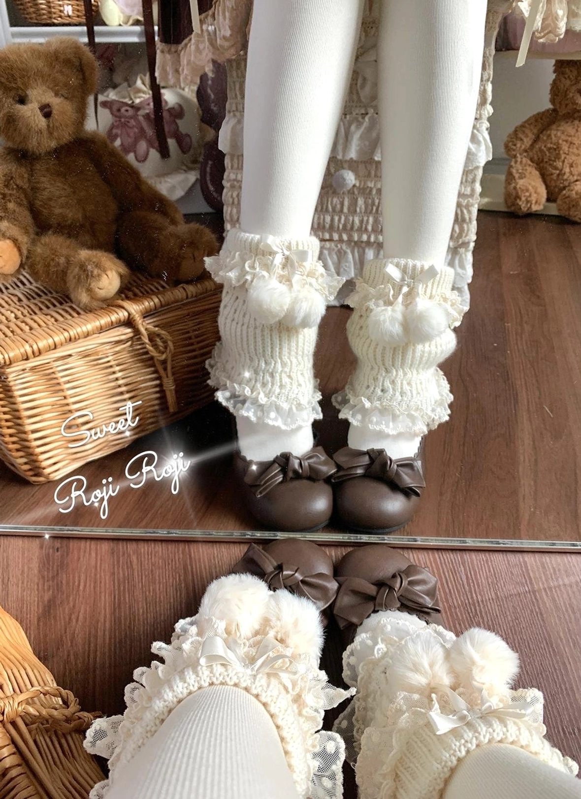 Cream lolita leg warmers close-up detail view showing layered lace ruffles, fuzzy pom-pom decorations, knitted fabric texture, worn with vintage plush toys