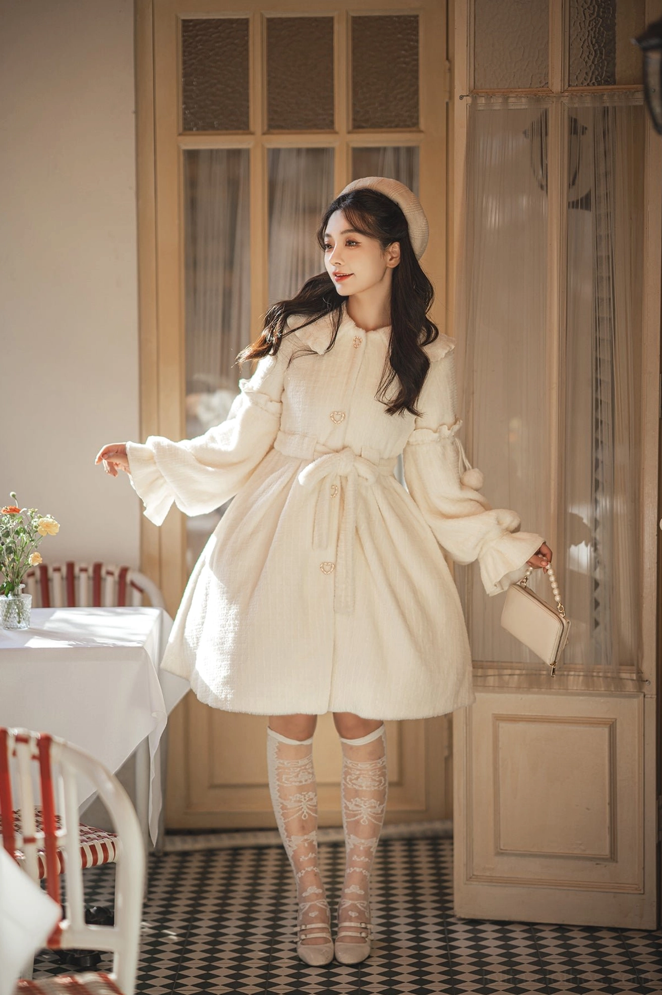 Cream puff winter lolita coat with heart-shaped buttons and removable pom-pom trims worn by model in vintage dining room setting, featuring round lapel collar and fluffy gold sable fabric