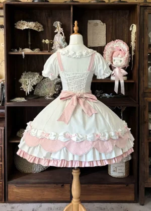 Cream rosette cake lolita JSK dress back view featuring elastic shirred back panel, large pink waist bow, and layered ruffled hemline with pink scalloped trim details