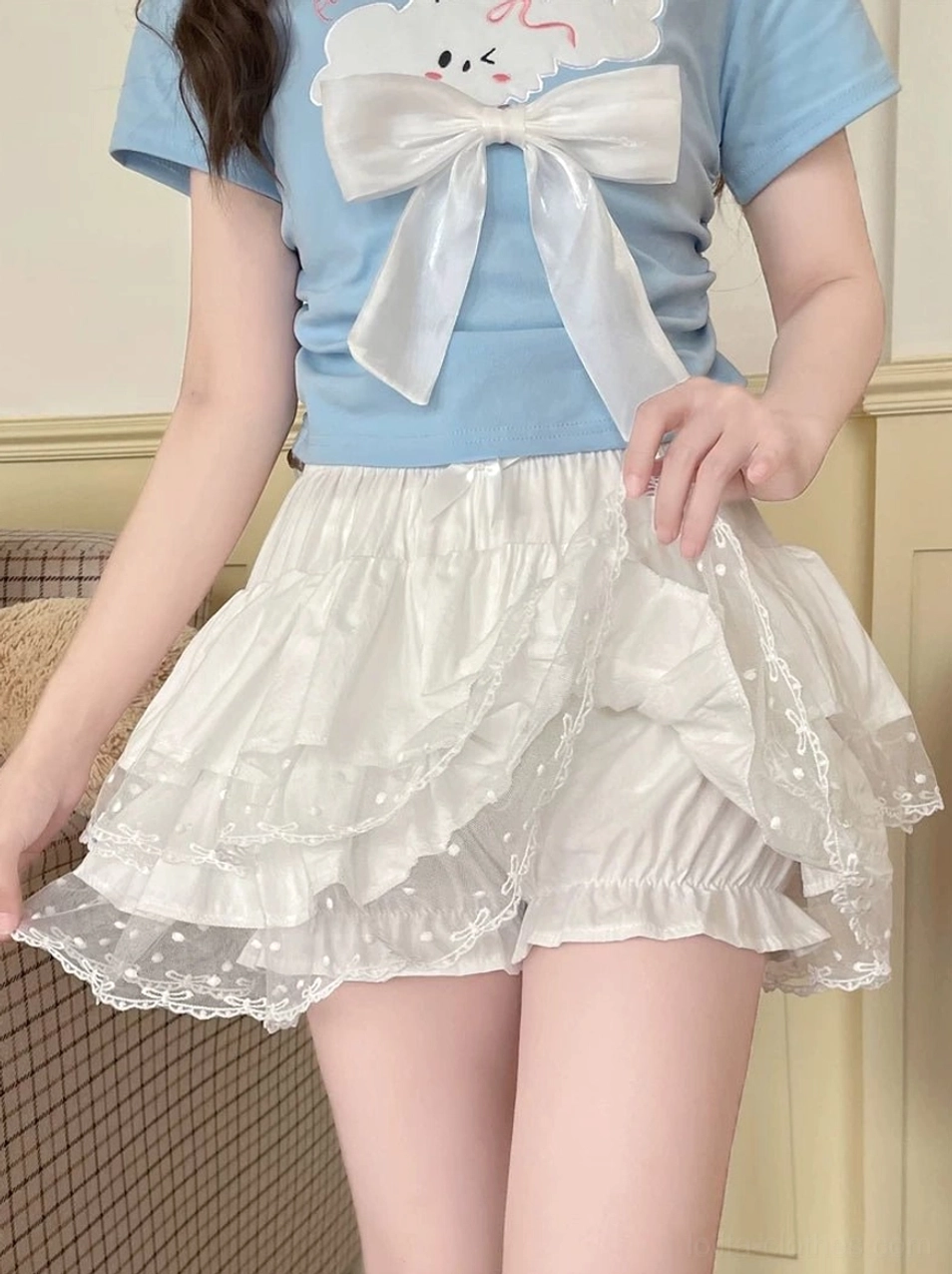 Cream white Lolita bloomer shorts full leg model showcase in retro sofa indoor setting paired with blue bow crop top showing layered ruffle construction and polka dot lace edge detail
