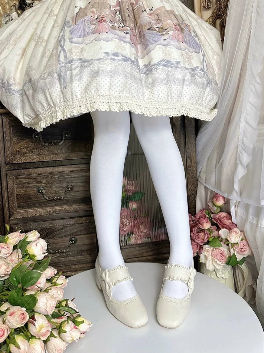 Cream white classic lolita chunky heel mary jane shoes with minimalist ruffled ankle strap and closed round toe, low front view of on-foot wear with vintage wooden dresser and floral decor
