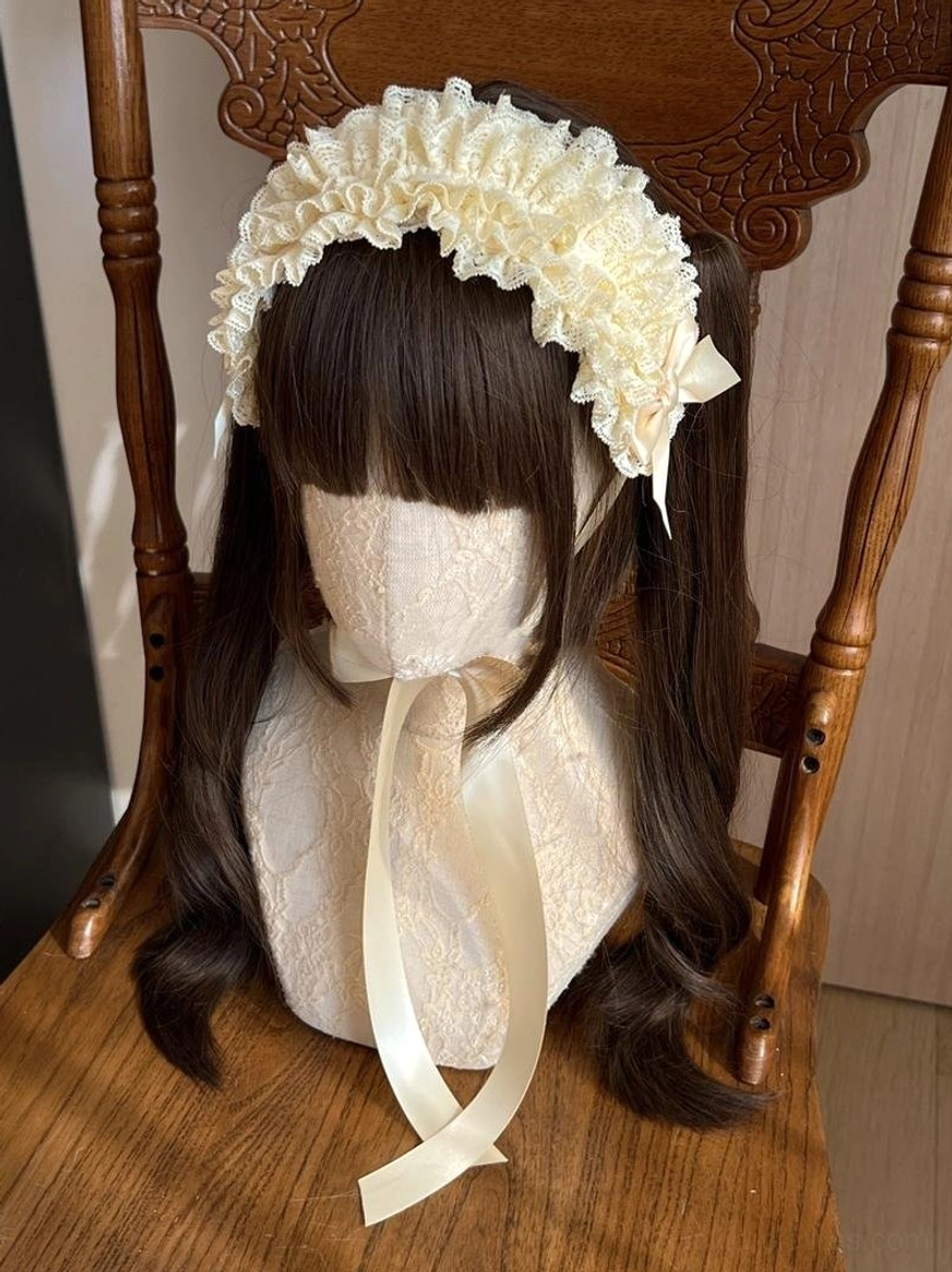 Cream yellow lolita lace KC headdress worn on mannequin with brown twin ponytails, featuring soft beige ruffled lace and matching satin bow with trailing ribbon